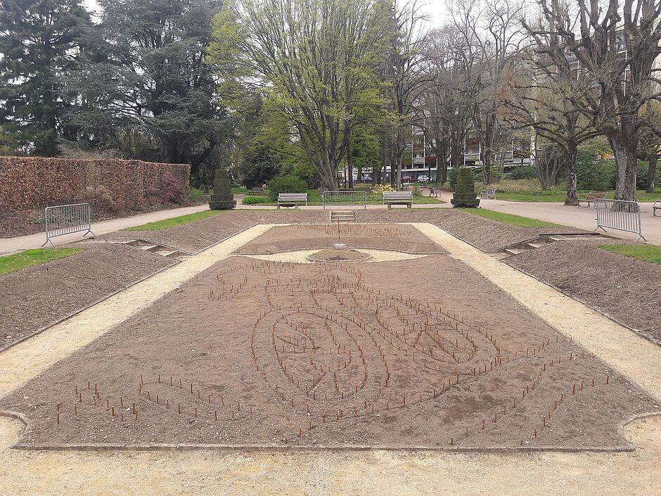 Vue du piquetage de petits bois servant à matérialiser le dessin de la mosaïque de la "partie basse" du square Emile Lechten.  - Agrandir l'image, . 0octets (fenêtre modale)