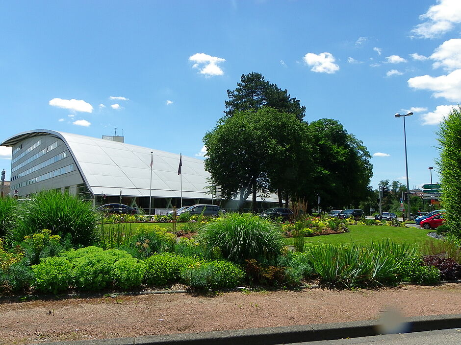 Massifs fleuris du carrefour de l'Espérance avec en arrière plan le centre de congrès ATRIA. Photo prise le 28 juin 2018. - Agrandir l'image, . 0octets (fenêtre modale)